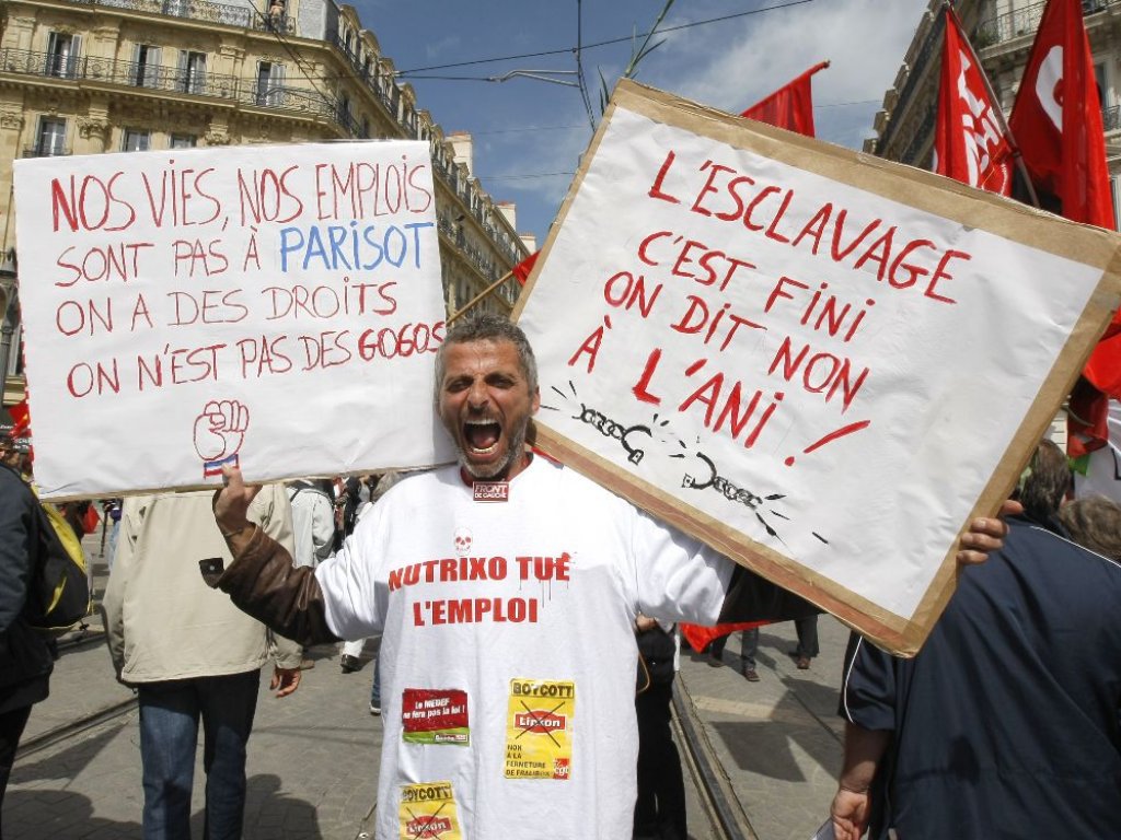 Un trabajador sostiene unas pancartas que decían "La esclavitud ha terminado, no a la ANI (reforma laboral del Gobierno) - nuestras vidas, nuestros trabajos no están en Parisot (jefe de jefes de los sindicatos), tenemos derechos, no somos idiotas!"