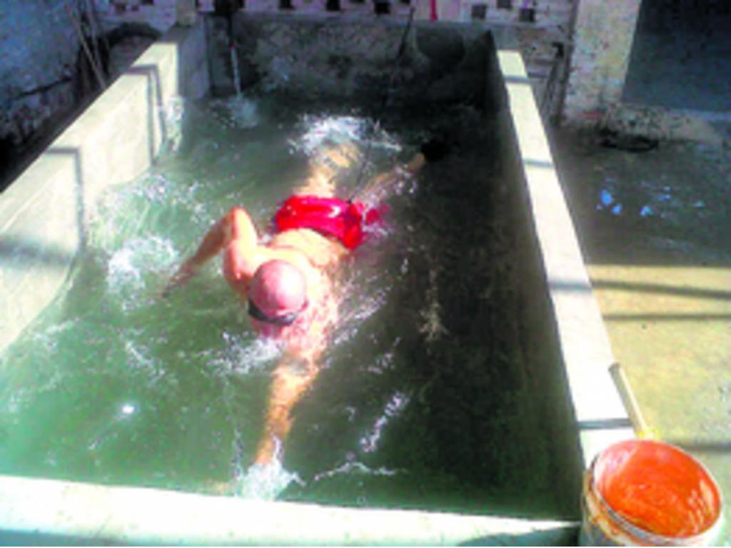 Edison Alexander Serna Serna se las ingenia para practicar la natación en una improvisada piscina en el patio de la parroquia, amarrándose la cintura.(Cortesía)
