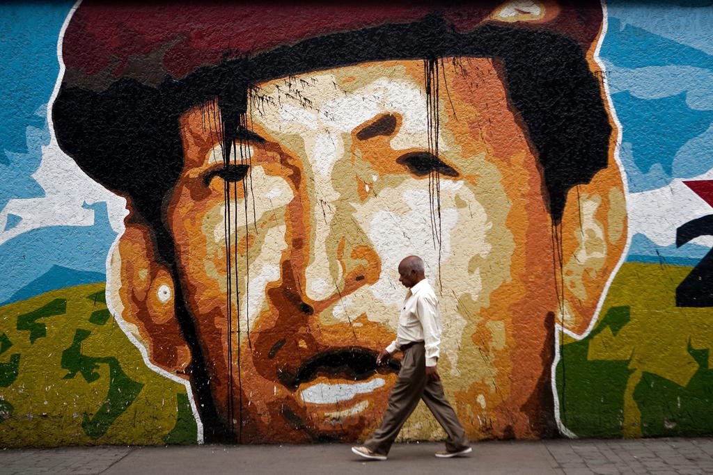 Un hombre camina junto a un mural del presidente venezolano, Hugo Chávez. EFE<br>