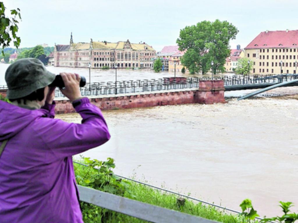 4- Una mujer observa el paso del agua bajo un puente en Grimma, Alemania.