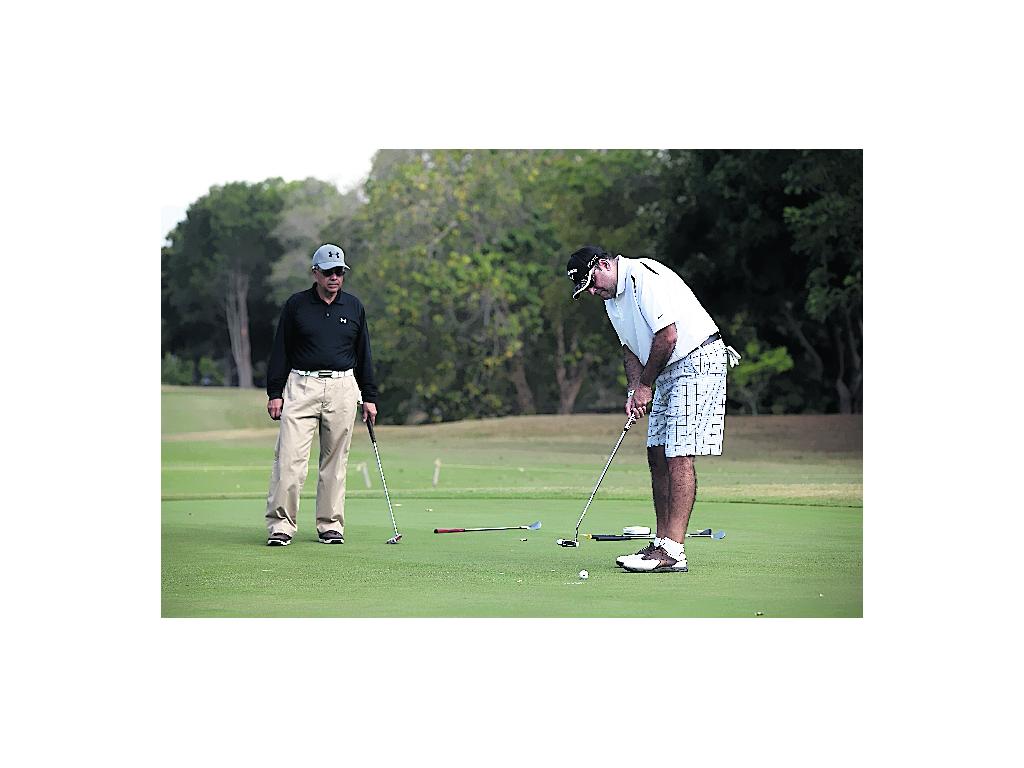 El señor Ramón Crespo (izq.) observa a su compañero de equipo Xavier Castillo (dcha.), mientras emboca la pelota en uno de los hoyos de la cancha del Coronado Golf and Resort, sede del torneo. ()