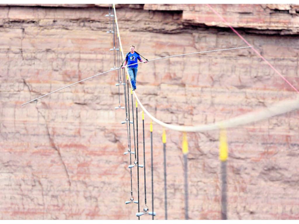 El predicador Joel Osteen (izq.) junto al funambulista Nik Wallenda y su familia orando antes de cruzar un tramo de 426,7 sobre el río Little Colorado.(EFE/Discovery Channel)