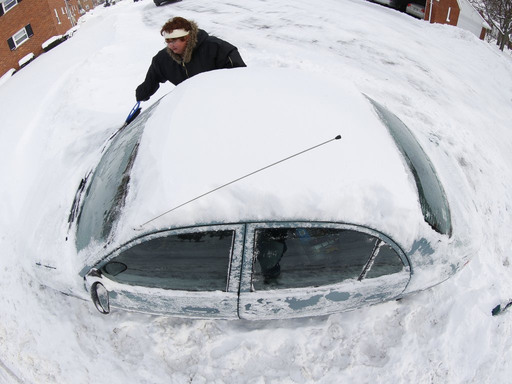 Marguerite Johnston de Grosse Pointe, Mich., desentierra su auto de la nieve.Foto/Con un objetivo de ojo de pez.AP