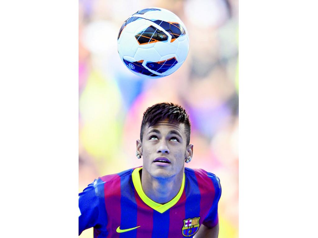 Neymar da Silva sostiene unas banderas de su nuevo club. (EFE)