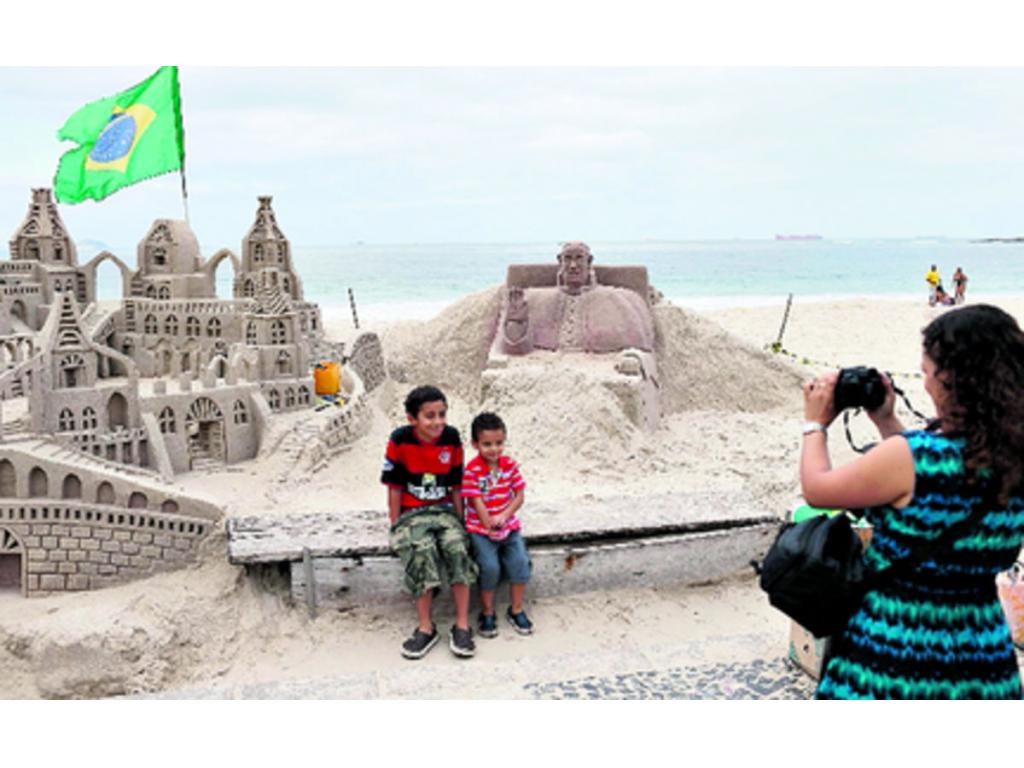 Niños posan junto a una escultura de arena del papa Francisco.(EFE)