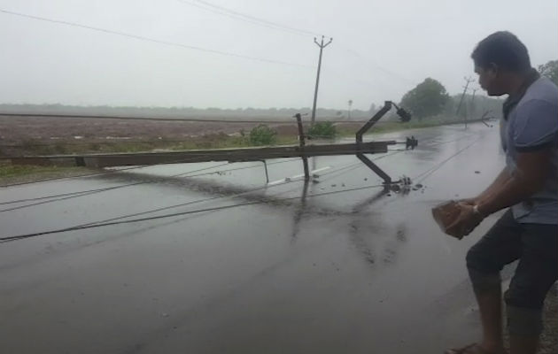 Un hombre sostiene un ladrillo para construir un desvío de la carretera para ayudar a los carros a evitar un poste eléctrico que cayó después del ciclón Gaja en la India. AP