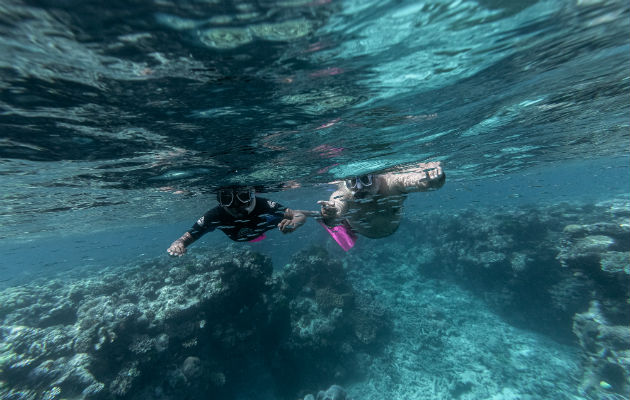 Murrumu de Walubara haciendo snórquel con su hijo en la Gran Barrera de Coral, que, dice, es territorio indígena. Foto/ Brook Mitchell para The New York Times.