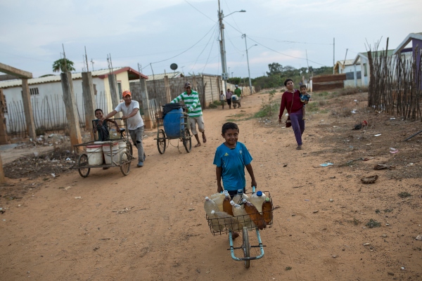 Residentes, jóvenes y viejos, empujan agua potable en el barrio de Villa Esperanza, en las afueras de Maracaibo. FOTO/AP