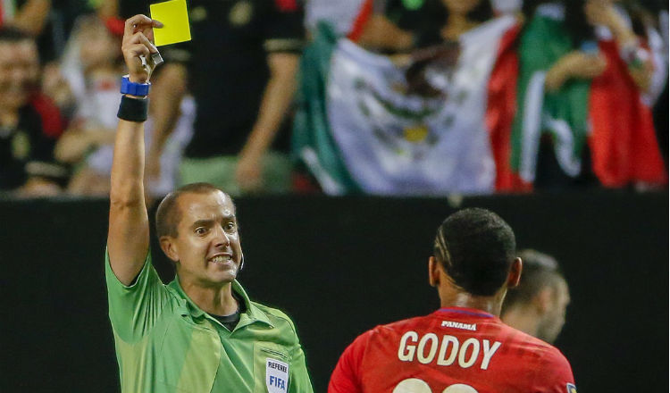 El árbitro Mark Geiger muestra tarjeta amarilla a Anibal Godoy. Foto:EFE 