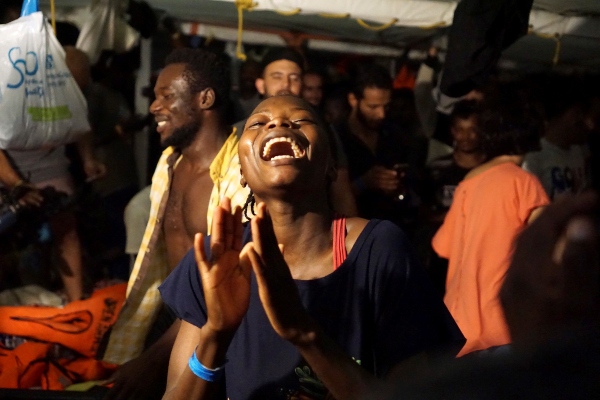 Varios migrantes esperan en el barco de la ONG española Open Arms, que sigue bloqueado desde hace 19 días frente a la isla italiana de Lampedusa. El buque militar español Audaz zarpó esta desde la base de Rota hacia Lampedusa para recoger y acompañar a España a los inmigrantes del Open Arms, casi de manera simultánea a que un fiscal italiano decretara su desembarco inmediato en la isla italiana y la incautación de la nave humanitaria. FOTO/EFE