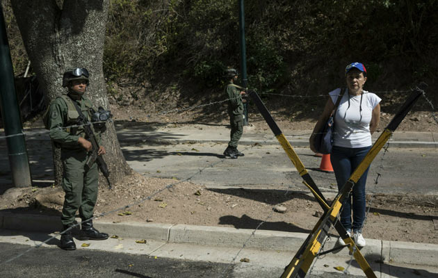 Una mujer está de pie junto a los soldados mientras otros miembros de la oposición entregan copias de una ley de amnistía cerca de Ft. La base militar de Tiuna en Caracas. FOTO/AP