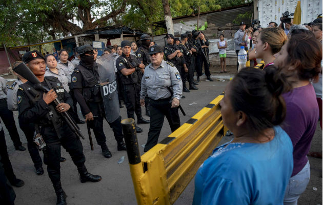 Antimotines de la Policía Nacional (izq) mantenían un cordón de seguridad frente a familiares de presos de la cárcel 