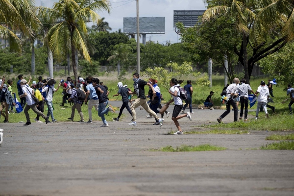 Varios jóvenes corren después que miembros de la policía nacional lanzaran bombas aturdidoras tras ser atacados con piedras por un grupo de manifestantes este domingo, en Managua (Nicaragua). FOTO/EFE