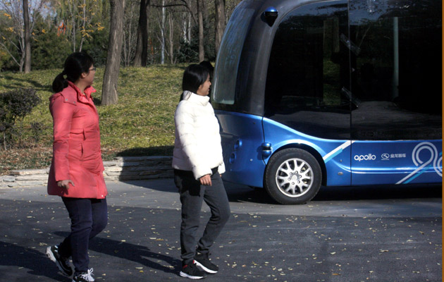 Un pequeño autobús, más alto que largo,  cruza sin pasajeros en su interior y a muy baja velocidad por delante de una marquesina donde esperan los visitantes.  FOTO/EFE