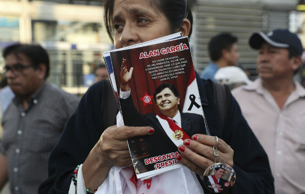 Una partidaria de Alan García afligida porta un retrato del expresiente. Foto: AP