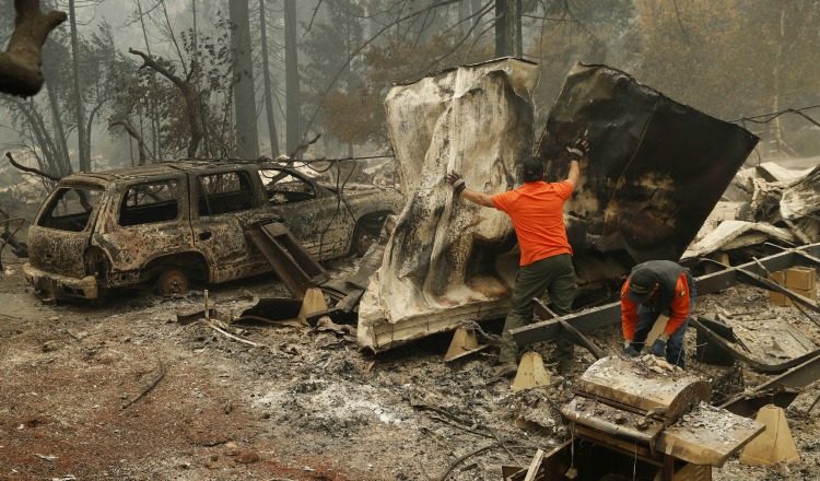Un socorrista busca restos humanos en un vehículo calcinado en un parque de autos en California. AP