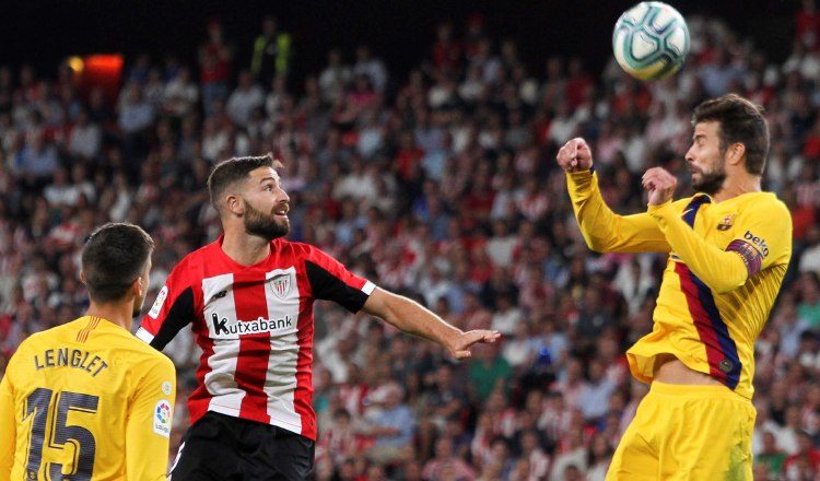 Gerard Piqué del Barcelona (der.) salta por el balón.