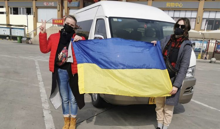 Los pasajeros ucranianos sostienen la bandera de su país antes de abordar un avión fletado. FOTO/AP