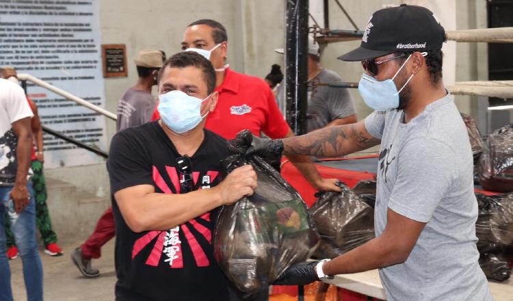 Anselmo "Chemito" Moreno (der.) entrega bolsas de comidas. Foto: Cortesía