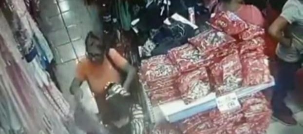 La señora se acrca a la joven que observa una mercancía y sin que ella si diera cuenta le saca lo que parece ser un monedero. 