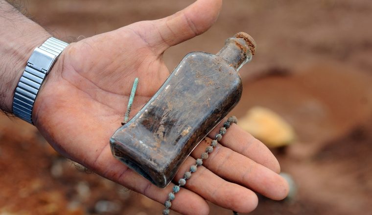 Botella de vidrio y cadena halladas en trabajos de excavación.    