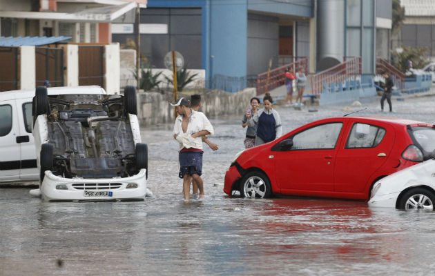 - Varias personas observan vehículos averiados por las inundaciones, en La Habana. FOTO/EFE