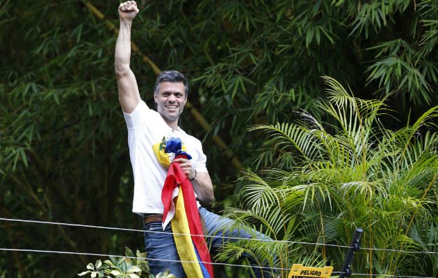 El líder opositor Leopoldo López saluda desde el muro de su casa a los simpatizantes. FOTO/AP