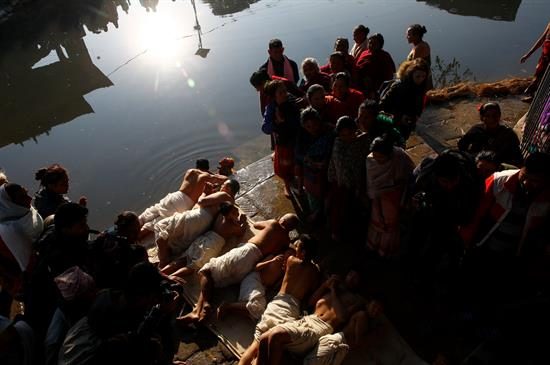 Devotos hindúes de Nepal ruedan en el suelo antes de tomar el baño. Foto: EFE