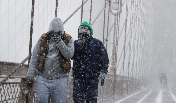Peatones se protegen de la nieve y del viento mientras cruzan el puente de Brooklyn. /Foto EFE