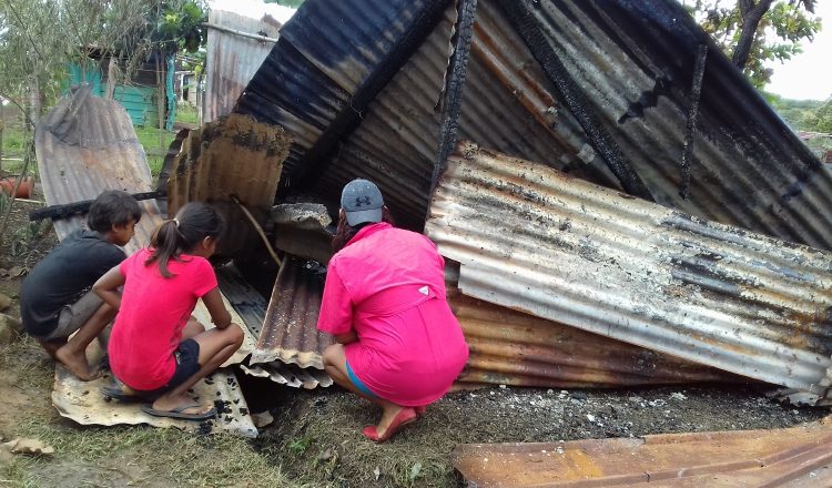 La mujer y sus hijos observan los restos de su humilde residencia, levantada con hojas de zinc, en un área de precaristas. /Foto Mayra Madrid