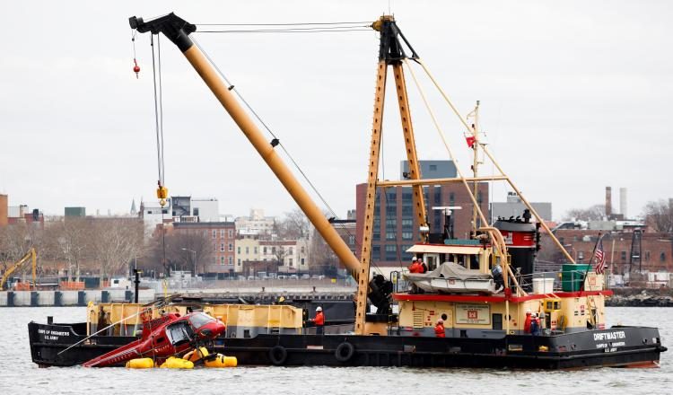 Una grúa saca un helicóptero en el estrecho del East River de Nueva York. EFE