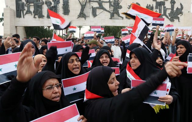 Un grupo de personas ondean banderas de Iraq y Siria, protestando contra el ataque a Siria. FOTO/AP