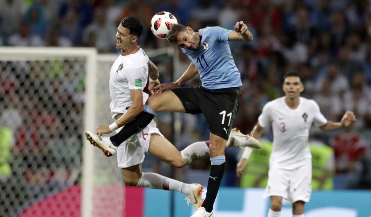 Cristhian Stuani (c) lucha por el balón con el luso José Fonte. /Foto AP