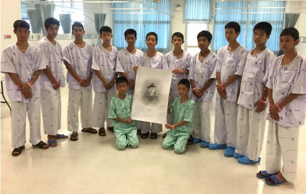 Una foto muestra a los 13 miembros del equipo de fútbol rescatado, sosteniendo un retrato del antiguo Navy Seal, suboficial 1 clase Saman Kunan, que murió durante los esfuerzos de rescate en la cueva. 