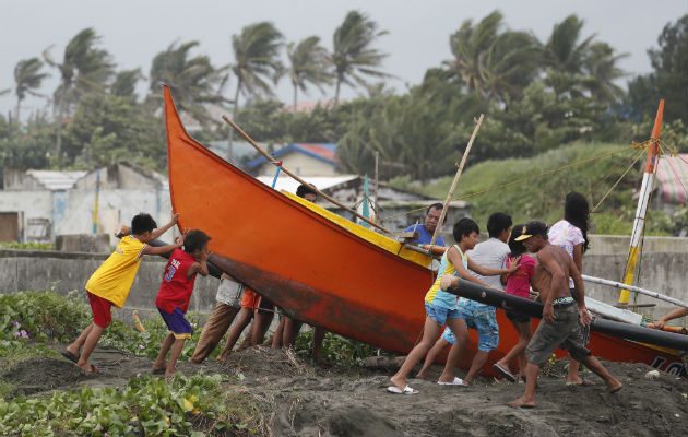 Pescadores y niños aseguran un bote antes de la llegada del tifón Mangkhut. Foto: EFE