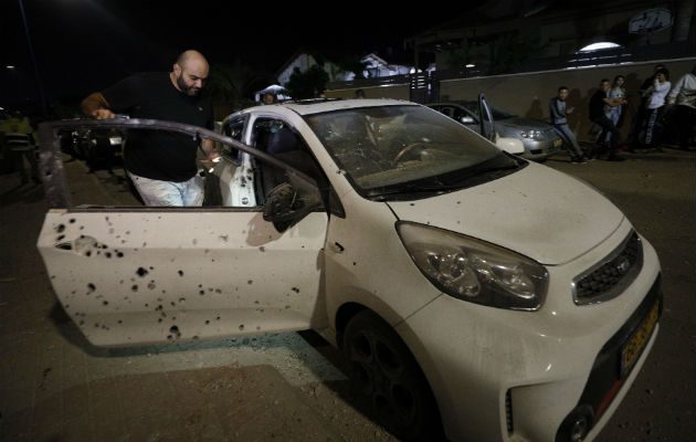 Un israelí observa su vehículo impactado por misiles tirados desde la Franja de Gaza. Foto: AP.