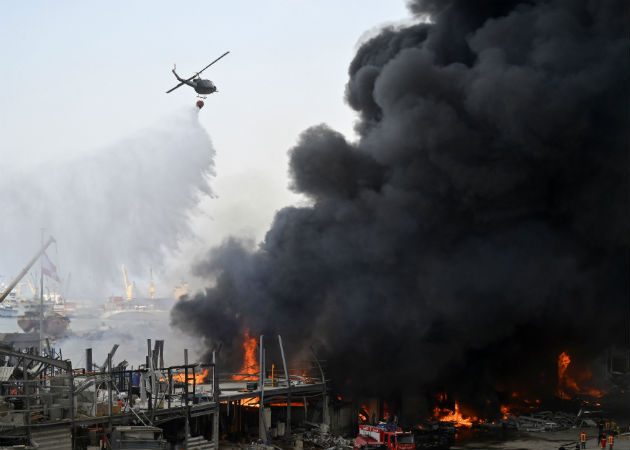 Un helicóptero de la armada lanza agua al fuego en el puerto de Beirut (Líbano). Fotos:EFE.