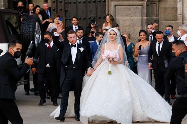 El campeón mundial de peso supermedio de la Asociación Mundial de Boxeo (AMB) y del Consejo Mundial de Boxeo (CMB) Saul "Canelo" Álvarez y su esposa Fernanda Gómez, saludan hoy, al salir de su boda en la catedral de Guadalajara, estado de Jalisco (México). 