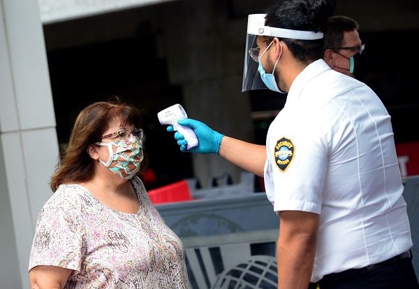 Un agente de seguridad de Universal Studios mide la temperatura a una señora que ingresa a dicho parque temático en Orlando, Florida (EE.UU).