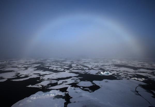 Un arco iris apareciendo en el horizonte en el Ártico.