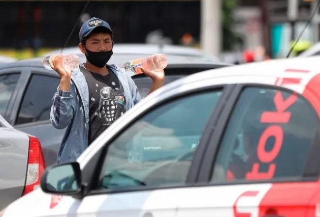 Un adolescente vende bebidas entre las filas de vehículos en Ciudad de México Foto: EFE