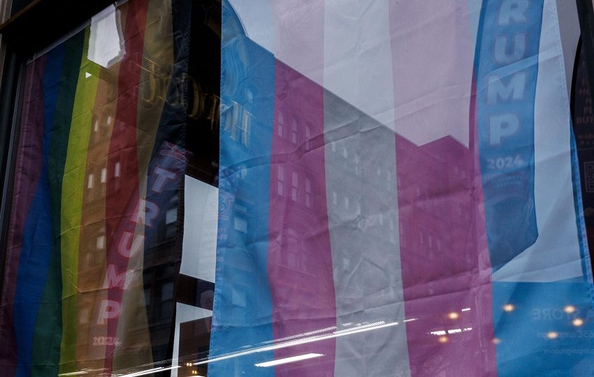 Fotografía de archivo de banderas alusivas a Donald Trump que se reflejan en una ventana que muestra banderas del Orgullo LGBTQ. Foto: EFE