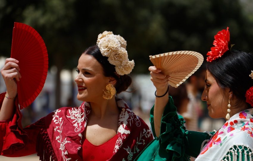 Varias mujeres vestidas de flamenca se cubren los ojos con abanico. Foto: EFE / Salas
