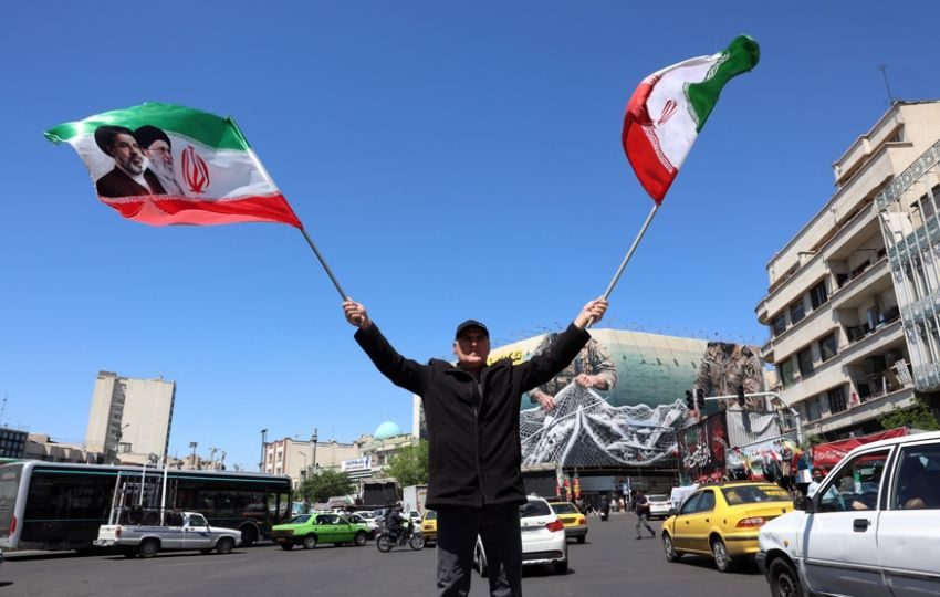 Un hombre ondea banderas iraníes en Teherán. Foto: EFE