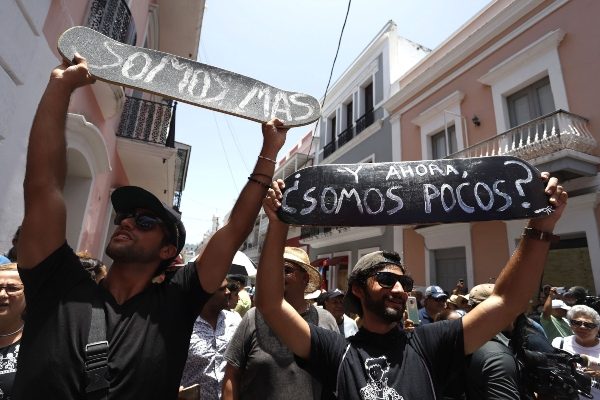 Manifestantes que esperan la renuncia del gobernador de Puerto Rico sostienen pancartas que dicen "Y ahora, ¿somos pocos?" y "Somos más" este miércoles durante el decimotercer día de protesta frente a La Fortaleza, sede del Ejecutivo, en el Viejo San Juan, Puerto Rico. FOTO/EFE