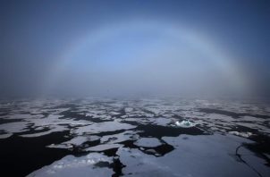 Un arco iris apareciendo en el horizonte en el Ártico. 