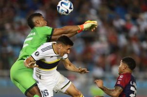El portero panameño Orlando Mosquera de Monagas despeja un balón  ante la llegada de Miguel Merentiel  de Boca Juniors  y la mirada de otro panameño Iván Anders