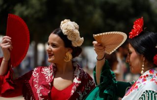 Varias mujeres vestidas de flamenca se cubren los ojos con abanico. Foto: EFE / Salas