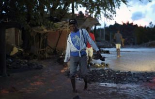 Una persona camina sobre el lodo tras la creciente del río La Digue. Foto: EFE