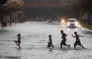 Un grupo de niños cruzaba por una calle inundada en Santo Domingo durante el paso del huracán Melissa. Foto: EFE